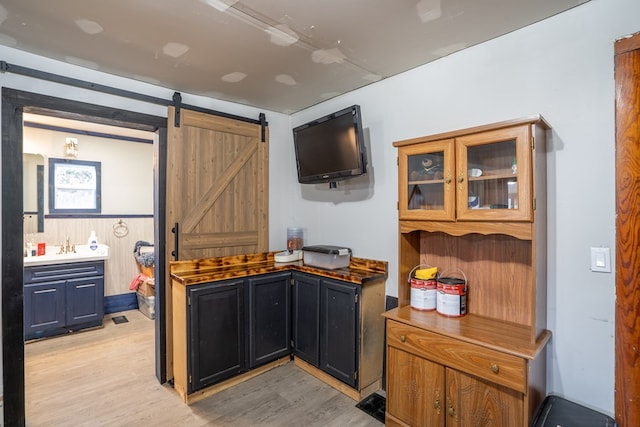 kitchen featuring a barn door, light hardwood / wood-style flooring, and wood walls