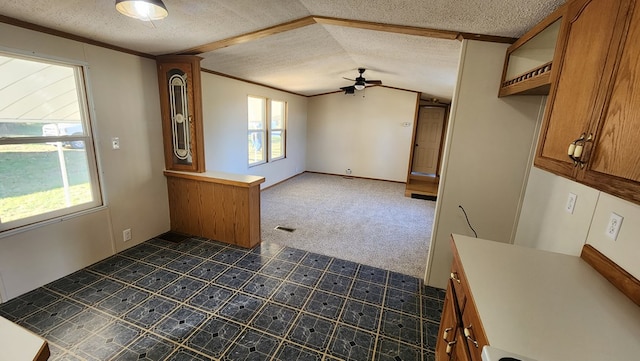 unfurnished living room with lofted ceiling, dark colored carpet, a textured ceiling, ornamental molding, and ceiling fan