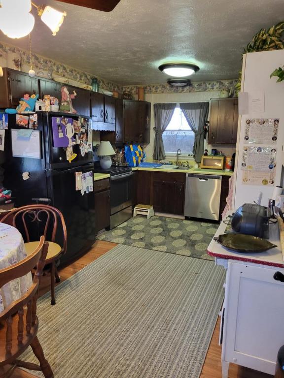 kitchen with sink, appliances with stainless steel finishes, dark brown cabinets, a textured ceiling, and light wood-type flooring