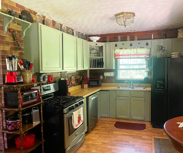 kitchen featuring sink, green cabinets, black appliances, a textured ceiling, and light wood-type flooring