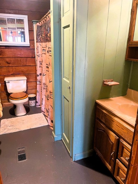 bathroom with vanity, wooden walls, and toilet