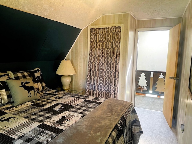 bedroom featuring vaulted ceiling, wooden walls, a textured ceiling, and carpet flooring