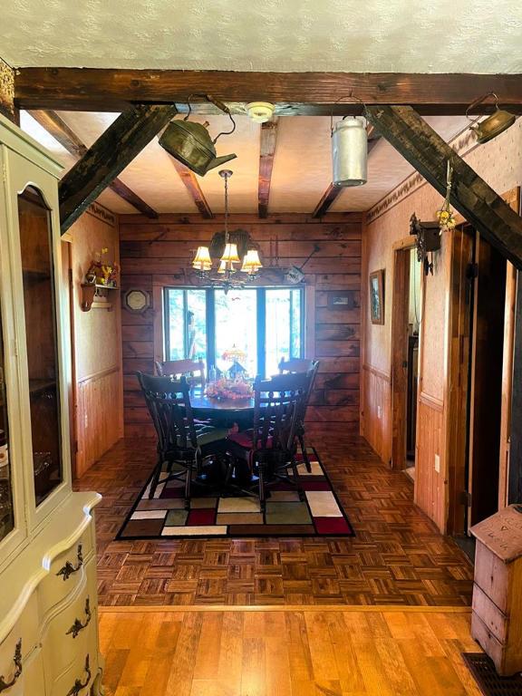 unfurnished dining area featuring a notable chandelier, beam ceiling, and wood walls