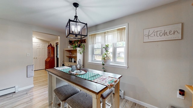 dining space with an inviting chandelier, a baseboard heating unit, light hardwood / wood-style flooring, and vaulted ceiling