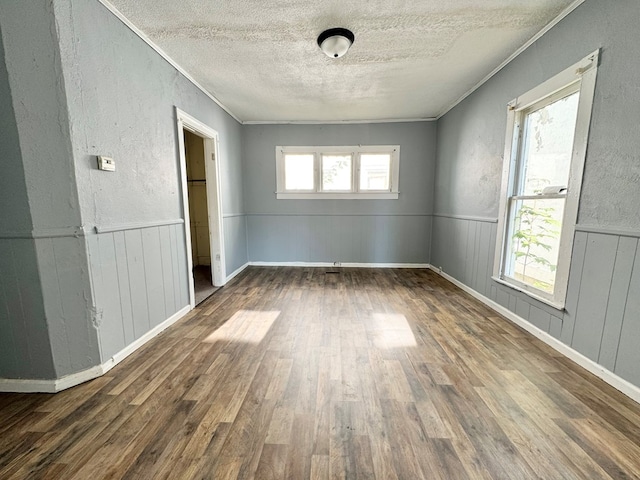 unfurnished bedroom with multiple windows, dark hardwood / wood-style flooring, ornamental molding, and a textured ceiling