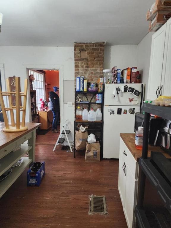 kitchen with white cabinetry, dark hardwood / wood-style flooring, and white fridge