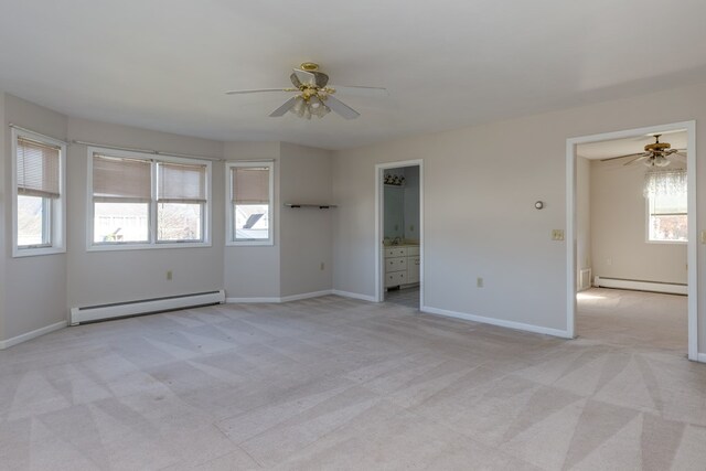 empty room featuring a healthy amount of sunlight, light carpet, and baseboard heating