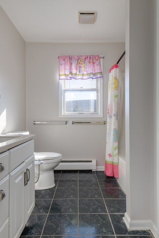 full bathroom with vanity, a baseboard heating unit, shower / bath combo, and toilet