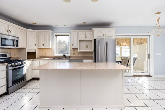 kitchen with appliances with stainless steel finishes, decorative light fixtures, sink, and a kitchen island