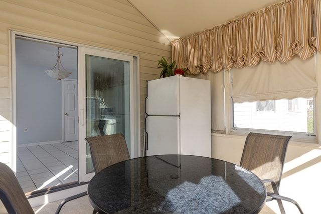 tiled dining space featuring vaulted ceiling