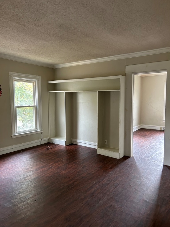 spare room with crown molding, dark wood-type flooring, and a textured ceiling