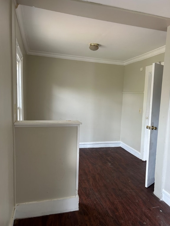 unfurnished room featuring dark wood-type flooring and ornamental molding