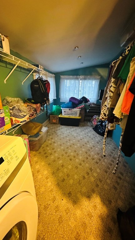 carpeted bedroom with lofted ceiling and washer / dryer