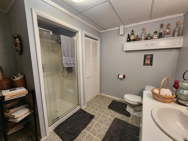 bathroom featuring toilet, a paneled ceiling, vanity, and walk in shower