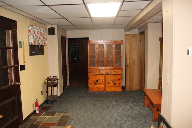 corridor with a drop ceiling and dark carpet