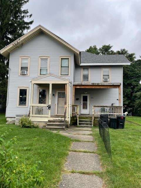 view of front of house with cooling unit, covered porch, and a front lawn