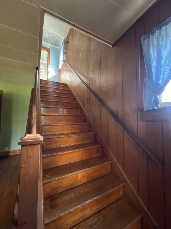 stairway featuring wood walls