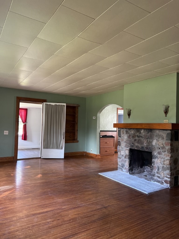 unfurnished living room featuring hardwood / wood-style floors and a stone fireplace