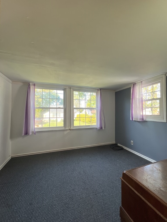 unfurnished room with crown molding and dark carpet