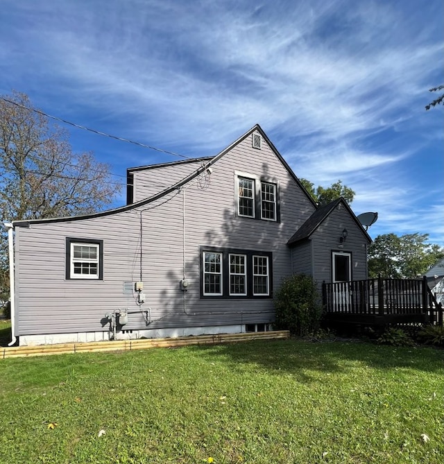 rear view of property featuring a deck and a lawn