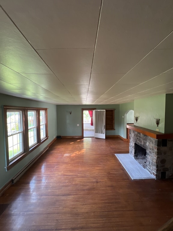 unfurnished living room featuring hardwood / wood-style flooring, a fireplace, and a baseboard radiator