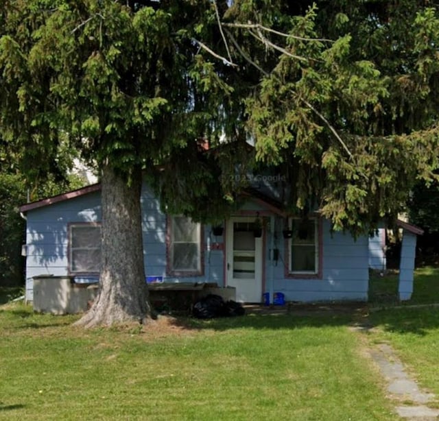 view of property hidden behind natural elements featuring a front yard