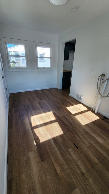 empty room with a healthy amount of sunlight and dark hardwood / wood-style floors