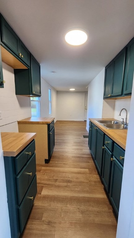 kitchen with wooden counters, sink, and light wood-type flooring