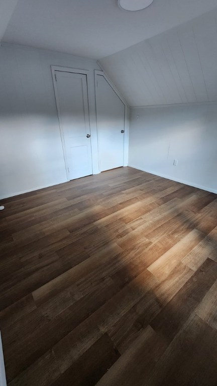 bonus room with dark hardwood / wood-style flooring and vaulted ceiling