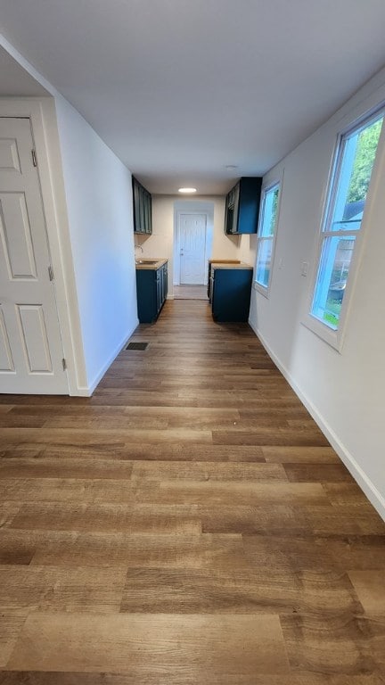 unfurnished living room featuring sink, a wealth of natural light, and dark wood-type flooring