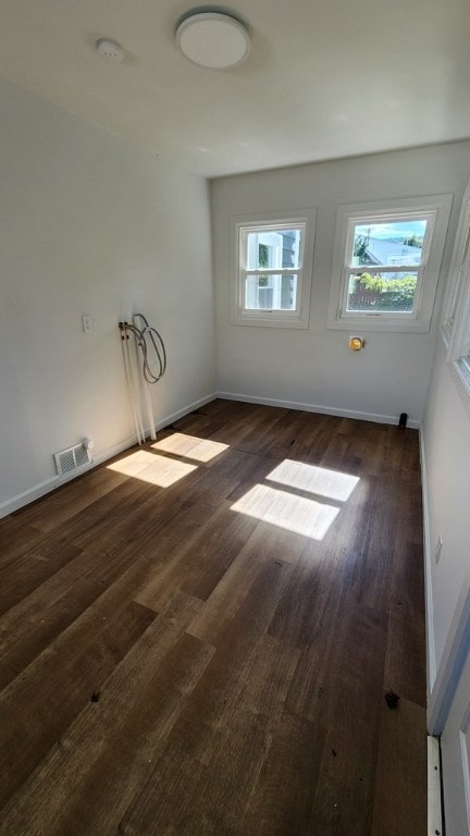 spare room featuring dark hardwood / wood-style flooring and a wealth of natural light