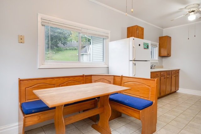 kitchen with light tile patterned flooring, ornamental molding, white fridge, breakfast area, and ceiling fan