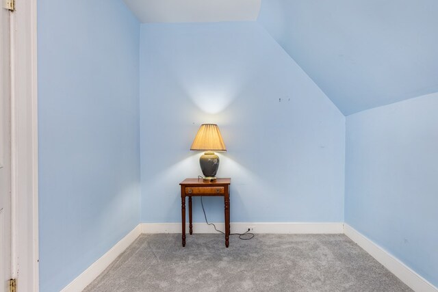 interior space featuring vaulted ceiling and light carpet