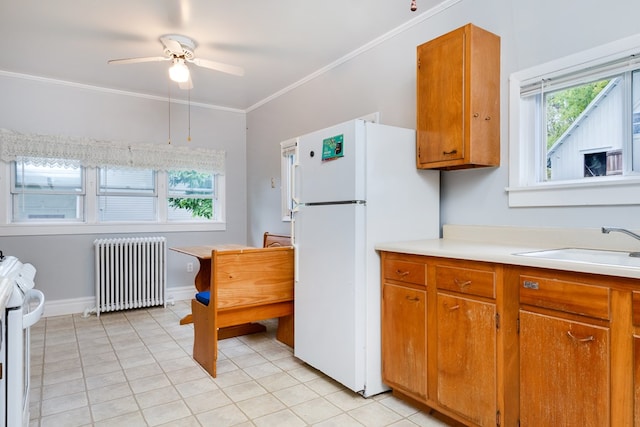 kitchen with radiator heating unit, sink, ornamental molding, ceiling fan, and white appliances