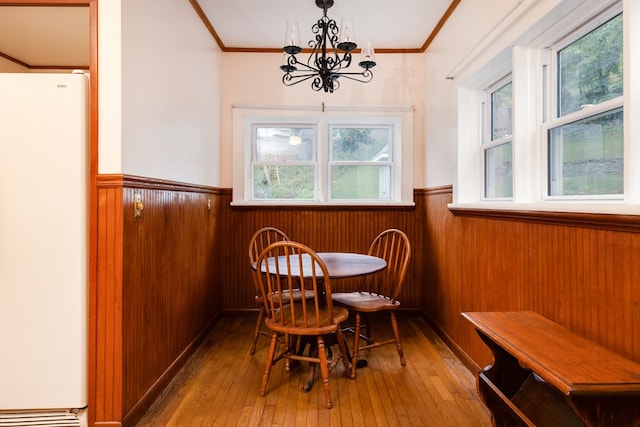 dining space with hardwood / wood-style flooring, ornamental molding, and wood walls