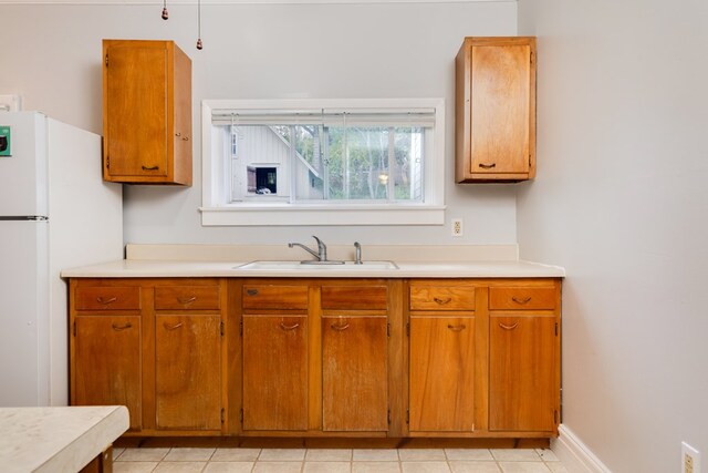 kitchen with sink, light tile patterned flooring, and white refrigerator