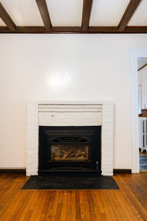 room details with beam ceiling, hardwood / wood-style flooring, and a fireplace