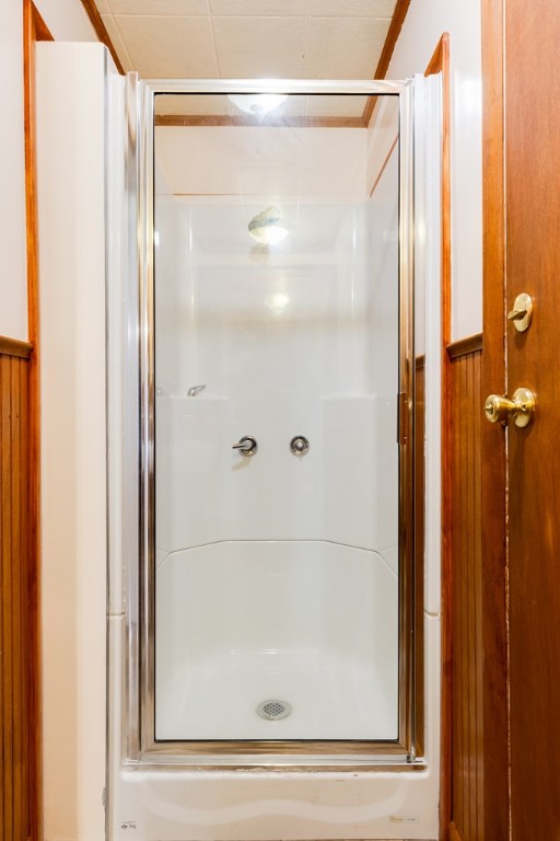 bathroom with a shower with door and wood walls