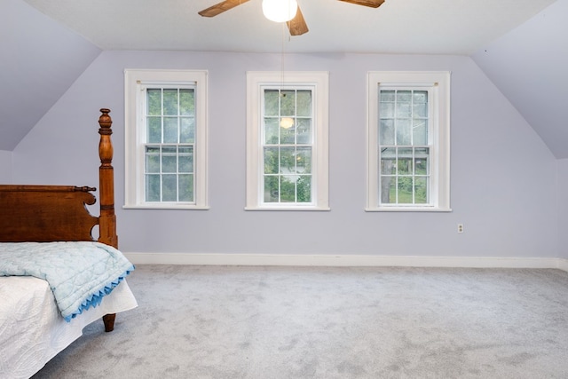 carpeted bedroom with ceiling fan, vaulted ceiling, and multiple windows