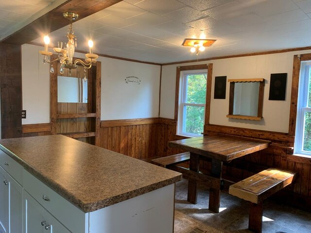 dining room featuring ornamental molding, wooden walls, and a notable chandelier