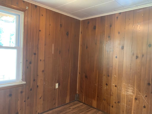 spare room with dark hardwood / wood-style flooring, crown molding, and wooden walls