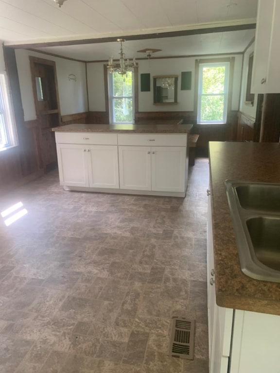 kitchen featuring sink, wooden walls, and white cabinets