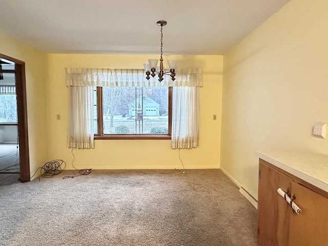 unfurnished dining area featuring a baseboard heating unit, carpet flooring, and a chandelier