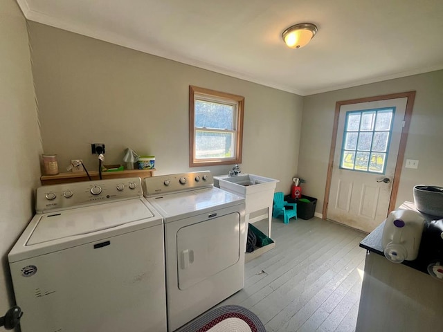 clothes washing area featuring crown molding, washer and clothes dryer, and light hardwood / wood-style floors