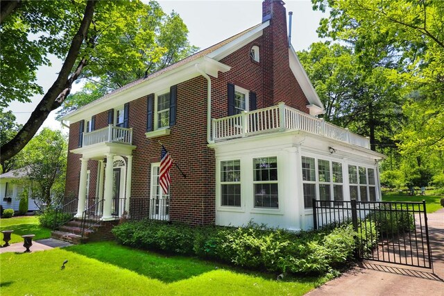 188 Upper Delevan Ave, Corning-City, NY 14830 - view of front facade with a balcony, brick siding, a front yard, and a chimney