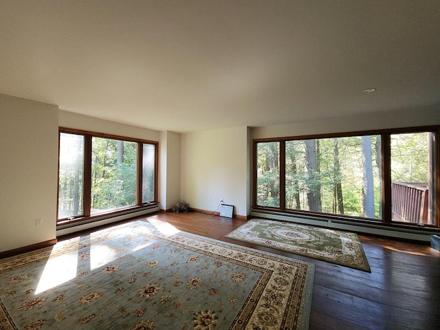 unfurnished room with hardwood / wood-style floors and a baseboard heating unit