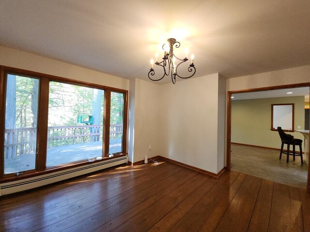 spare room with baseboard heating, a chandelier, and dark wood-type flooring