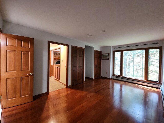 spare room with dark hardwood / wood-style flooring, a wall mounted air conditioner, and a baseboard heating unit