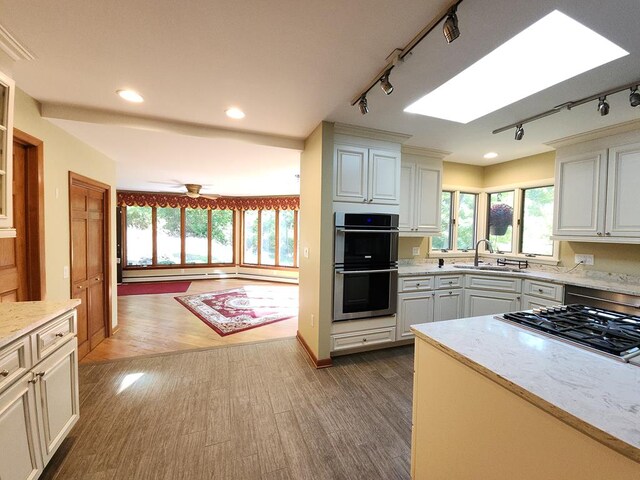 kitchen featuring sink, ceiling fan, appliances with stainless steel finishes, white cabinetry, and wood-type flooring