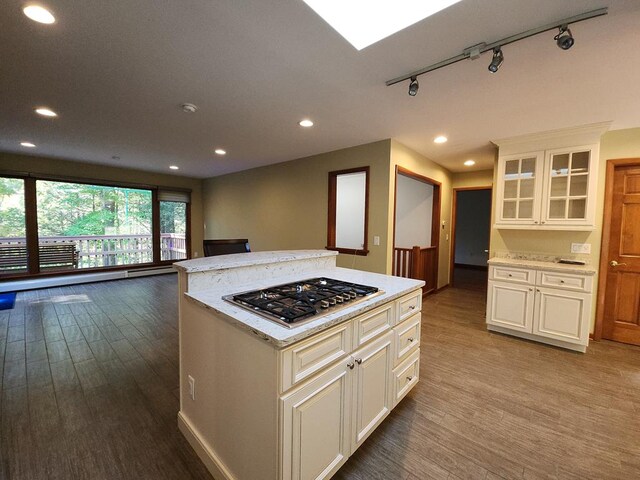 kitchen featuring light hardwood / wood-style flooring, a center island, light stone counters, track lighting, and stainless steel gas stovetop